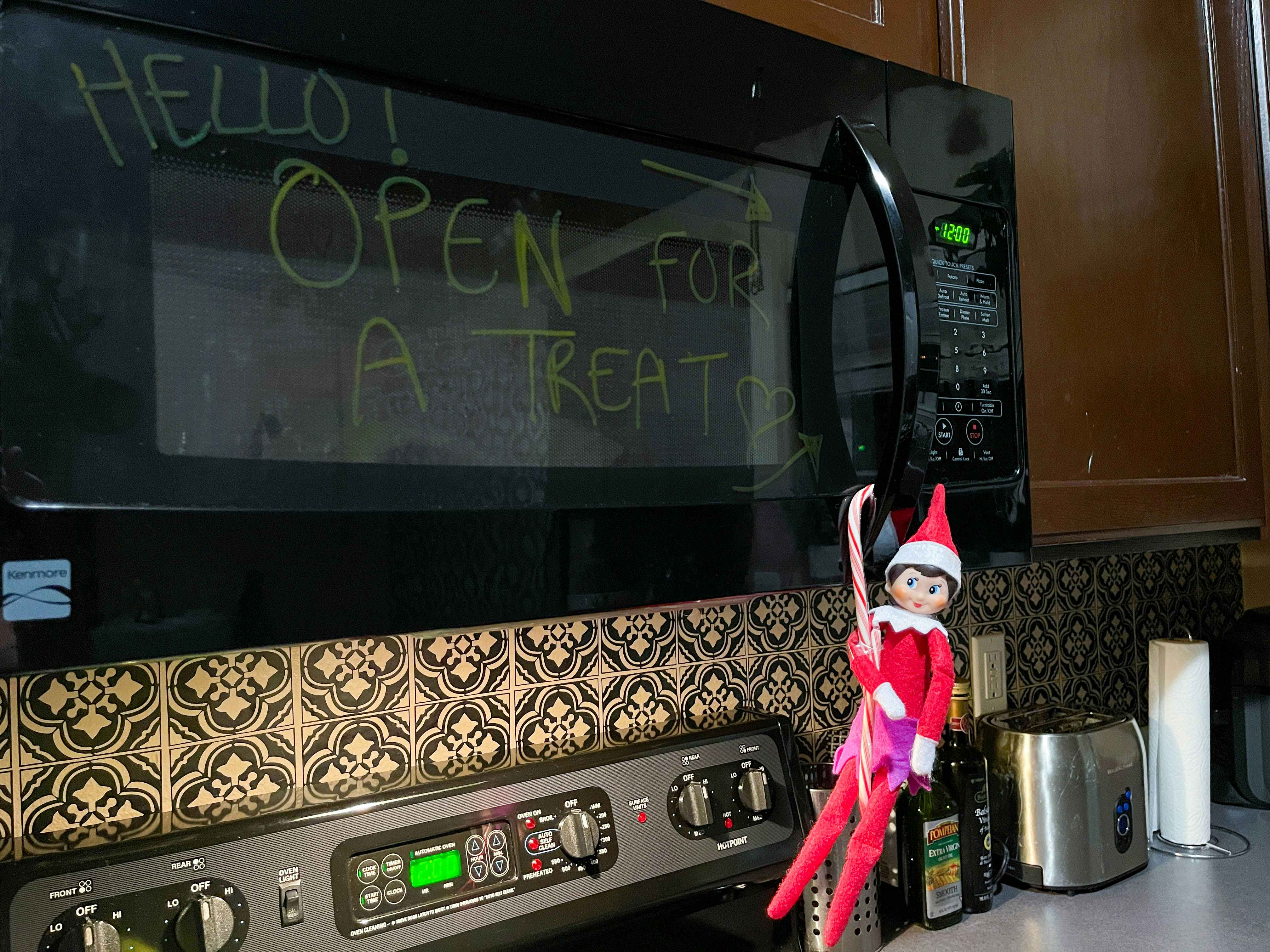 elf on the shelf hanging on the microwave with candy canes