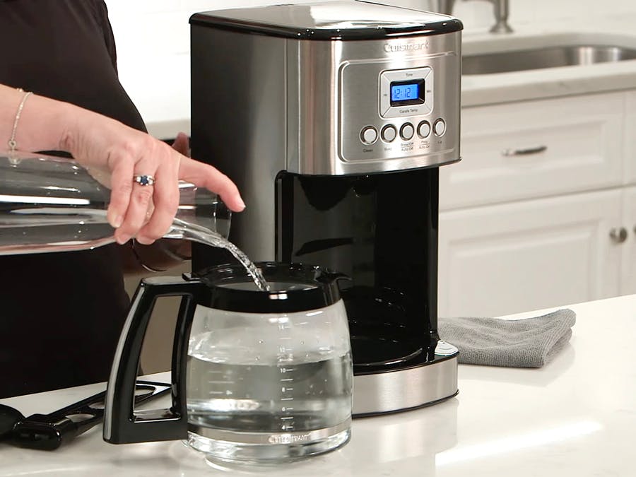 person cleaning cuisinart coffee maker with water-vinegar solution