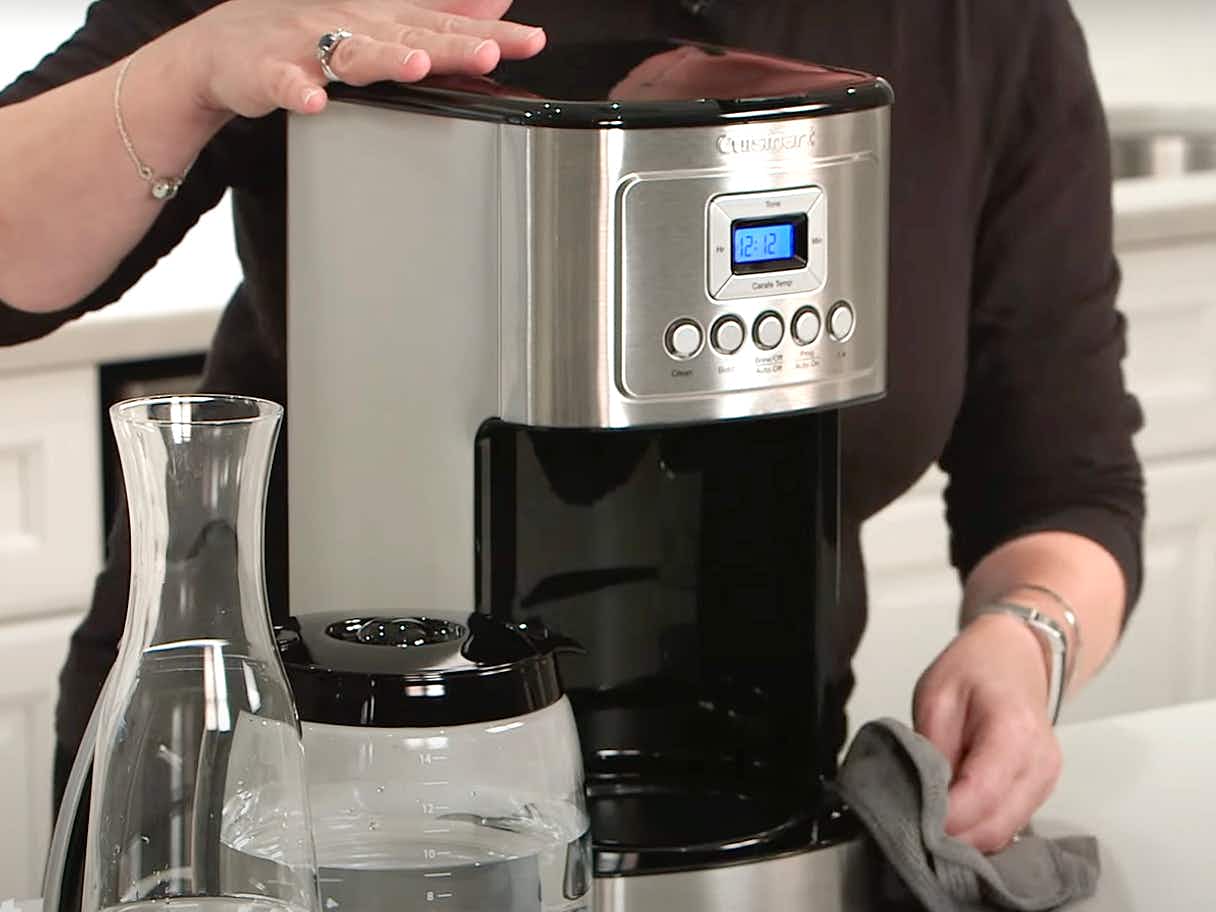 person cleaning a cuisinart coffee machine by wiping with towel