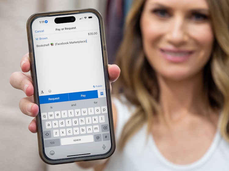 A woman holding out a cell phone displaying a Venmo payment she is about to send for a bookshelf