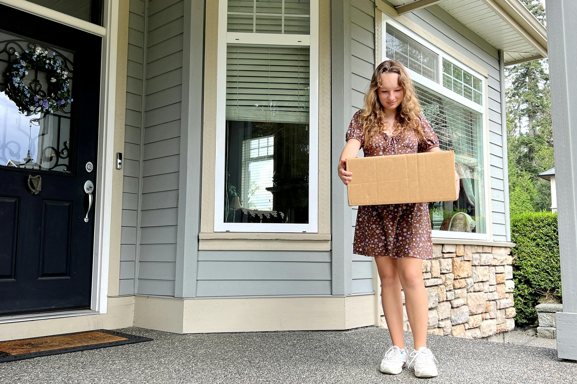 A person standing on a front porch with a shipping box
