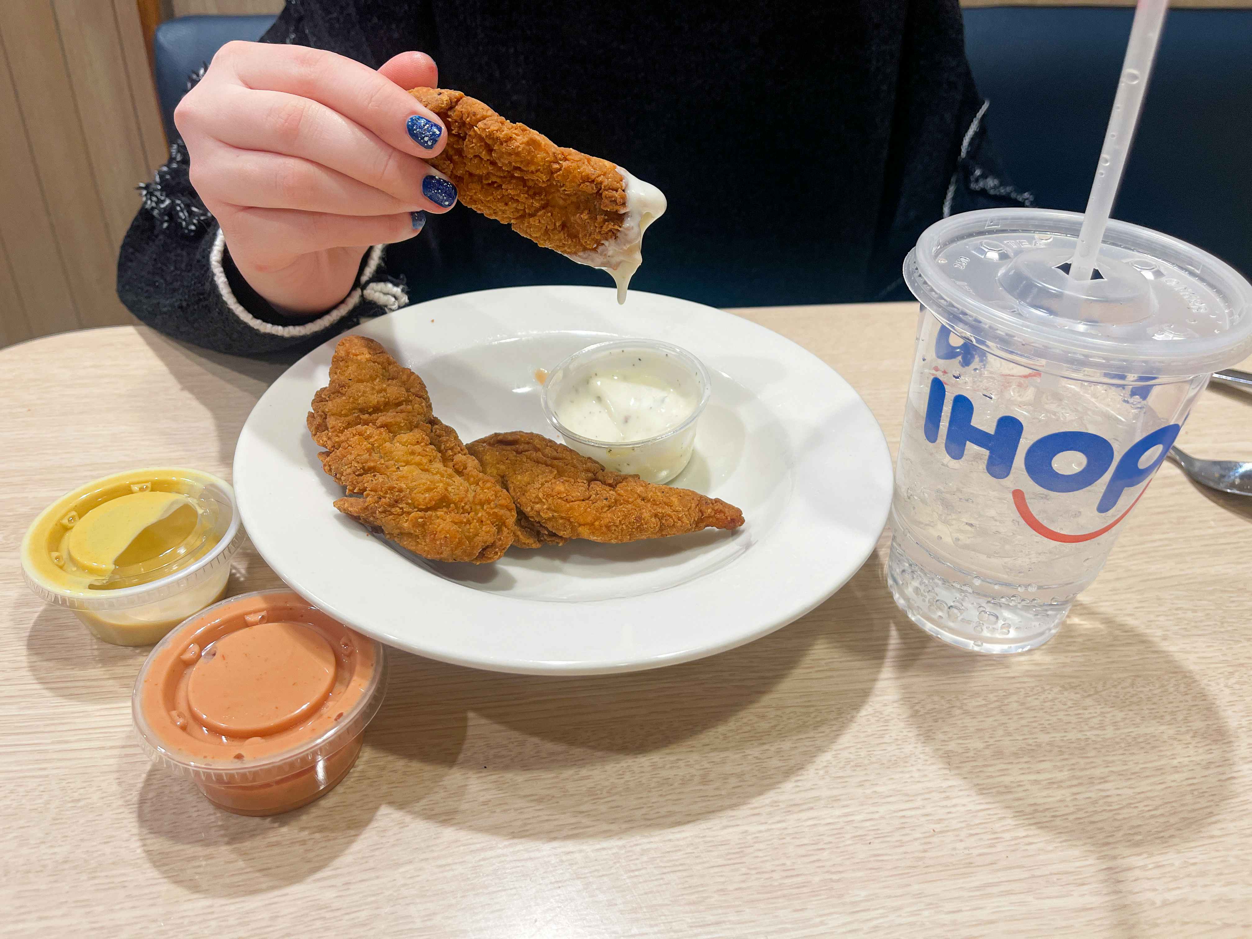 Someone dipping a Crispy Chicken Strip into some ranch at IHOP