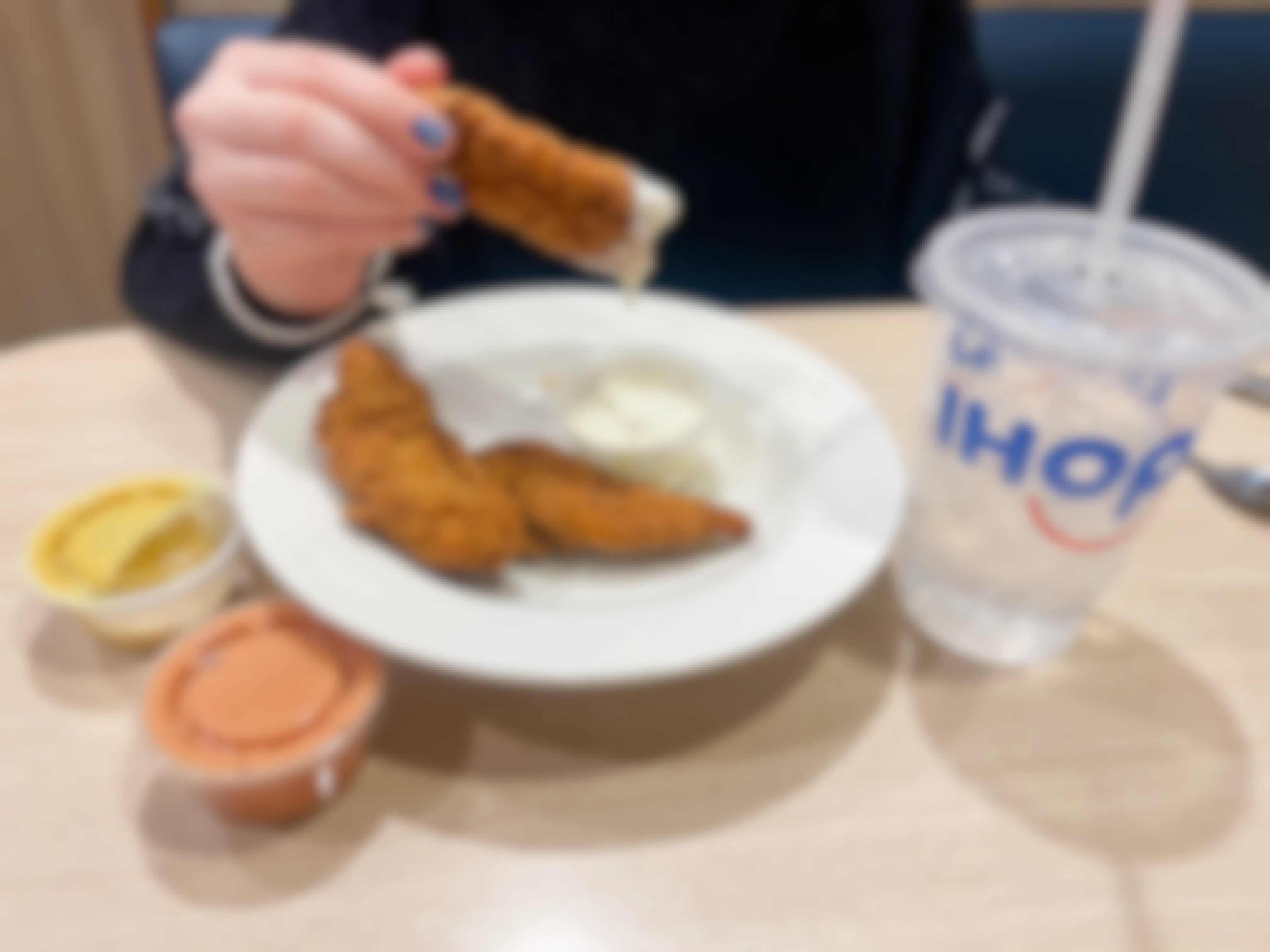 Someone dipping a Crispy Chicken Strip into some ranch at IHOP