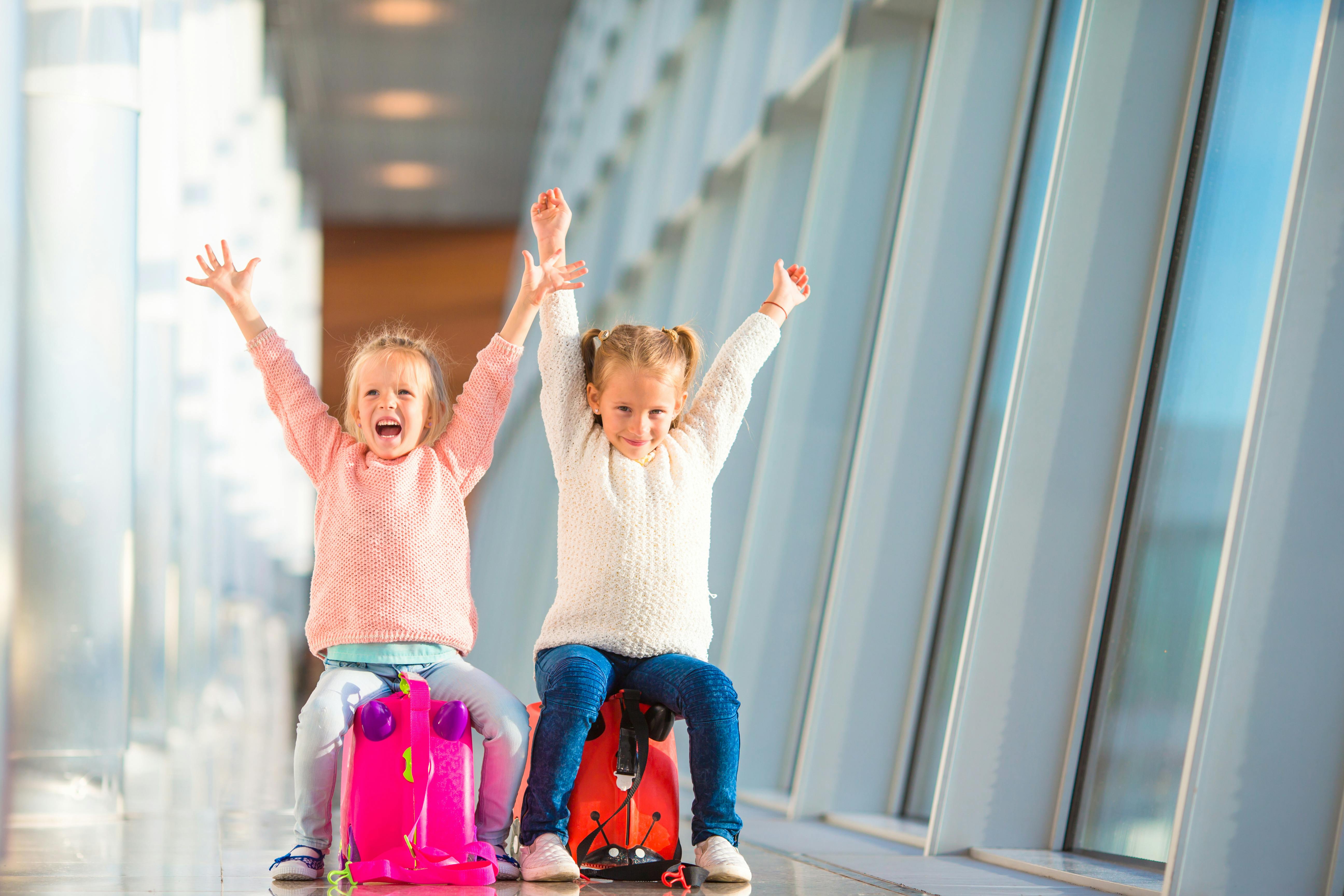 Kids using a ride-on luggage at an airport