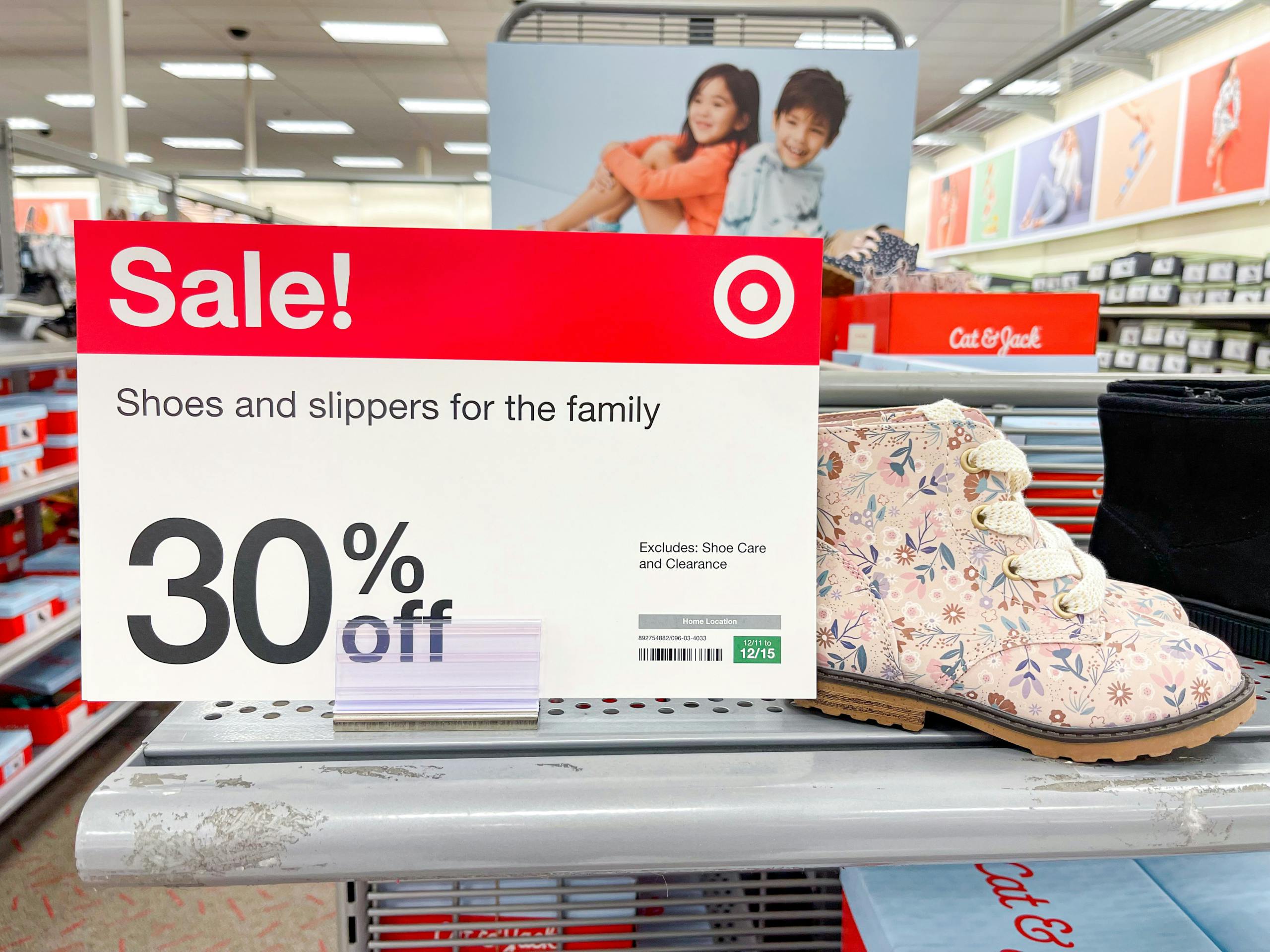 A pair of kid boots sitting on a store shelf next to a Sale sign.