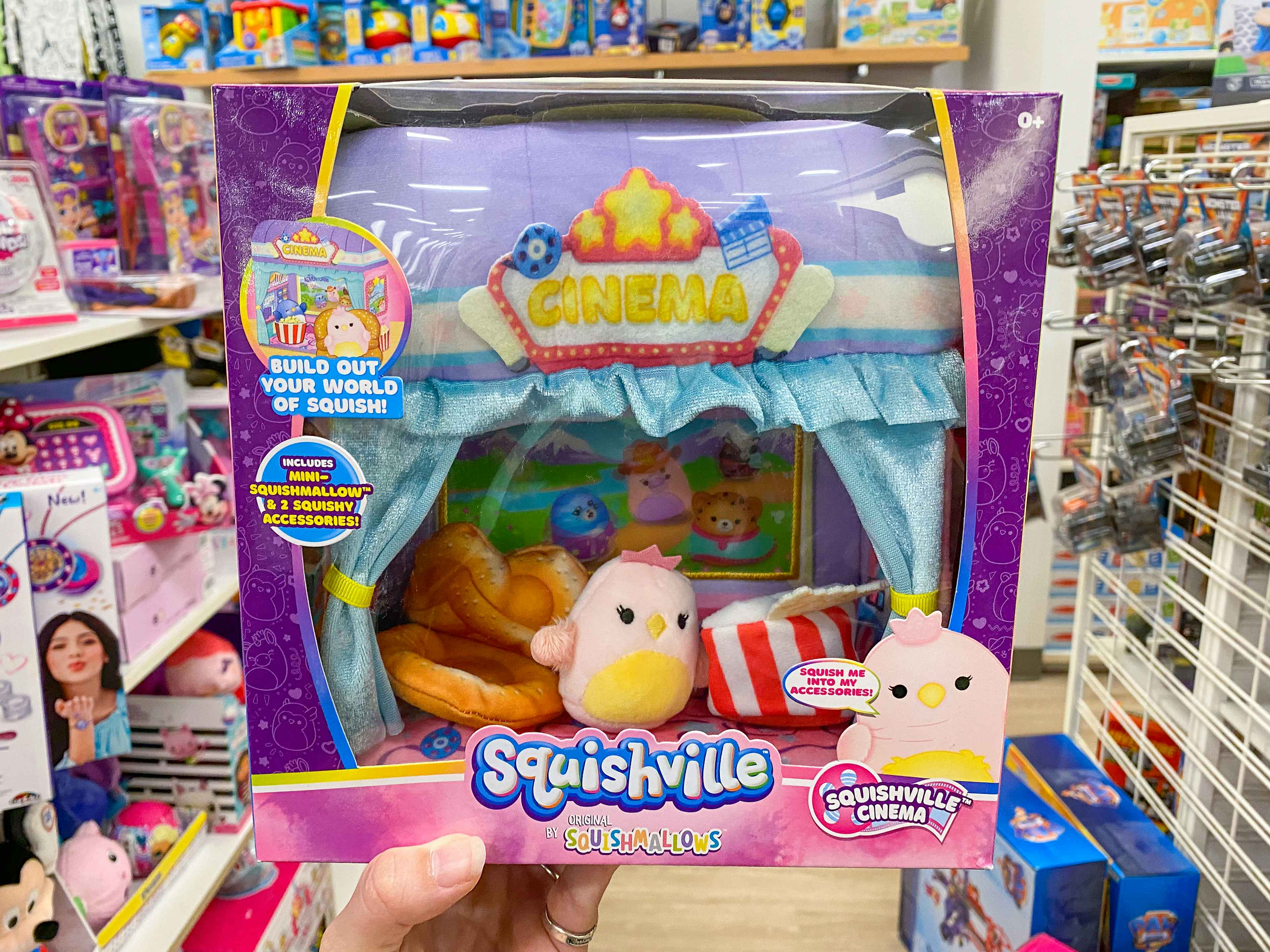 Someone holding up a Squishmallows Squishville Cinema collectible set in a toy aisle