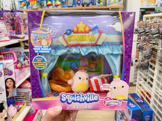 Someone holding up a Squishmallows Squishville Cinema collectible set in a toy aisle