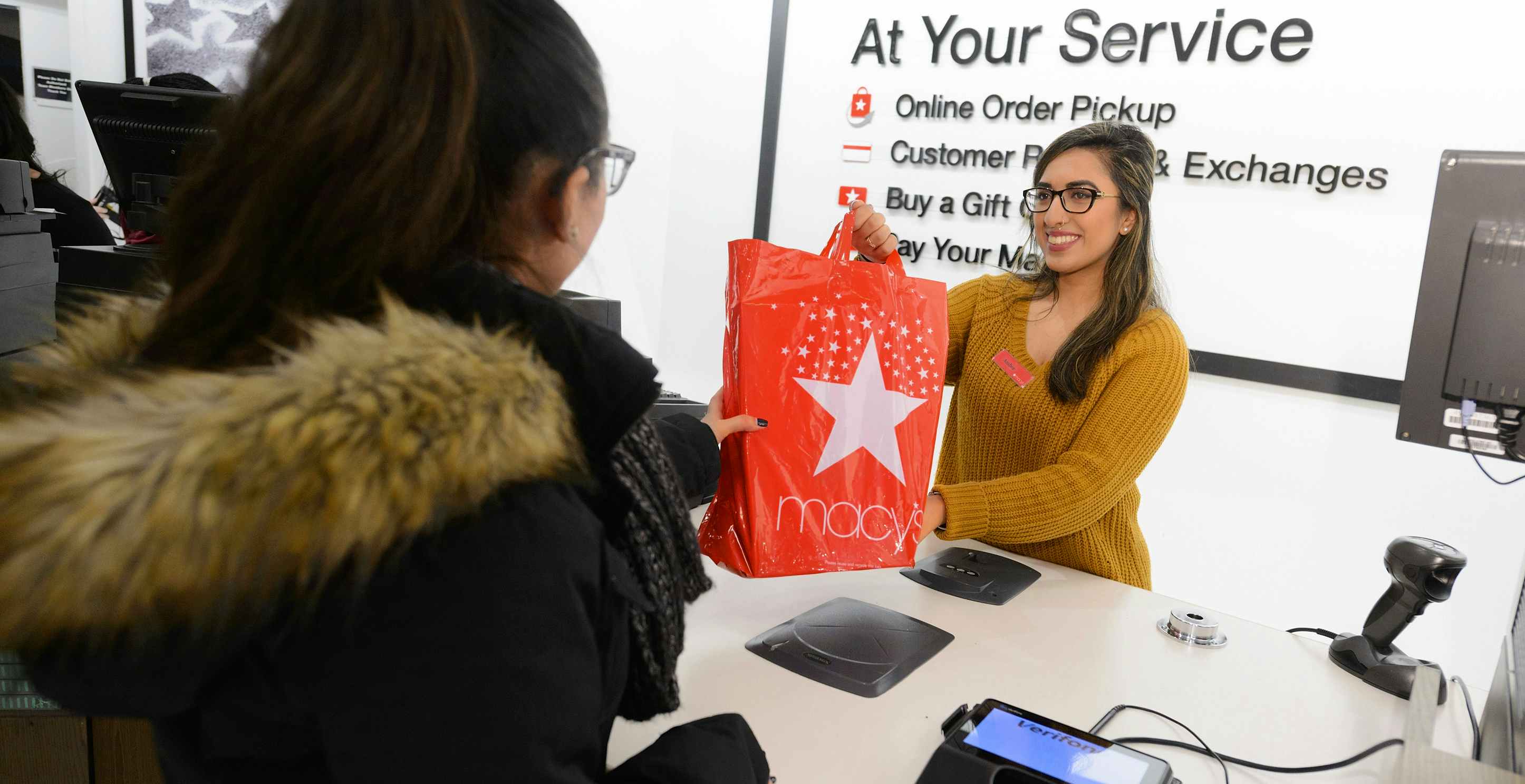 macys customer service cashier handing order pickup bag to customer