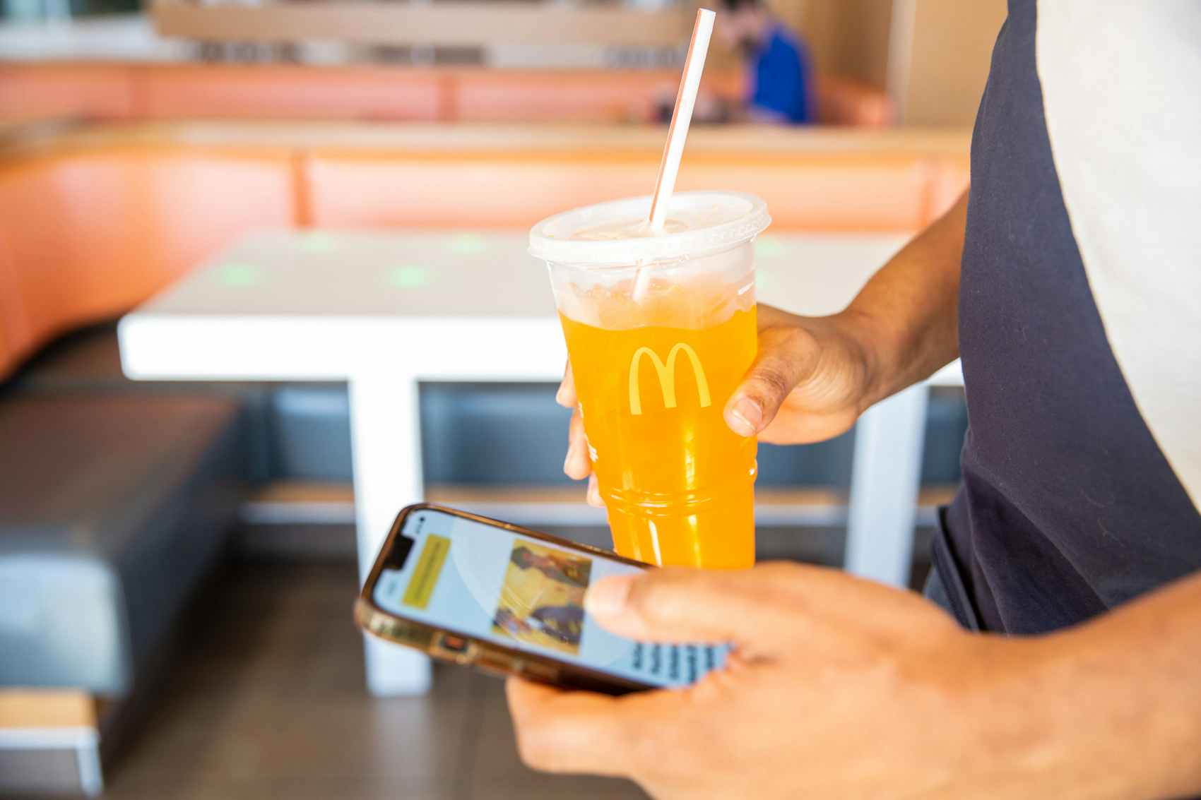 Person on their phone looking at the Mcdonalds app while holding a Soda cup from McDonalds
