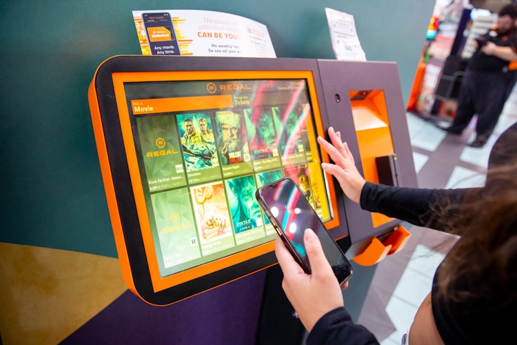 Someone selecting a movie on the Regal ticket kiosk