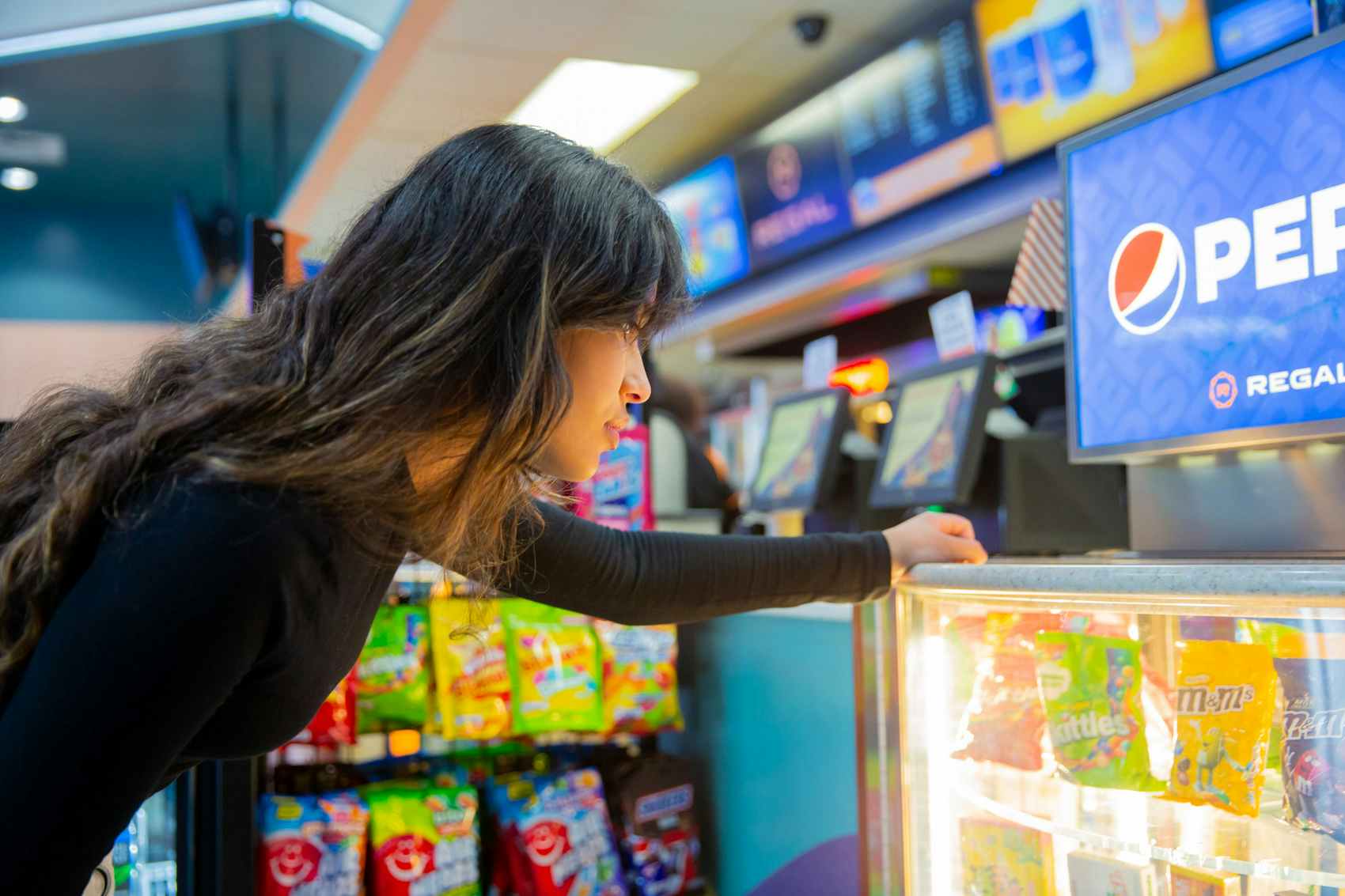 Woman looking at candy by the concessions stand inside Regal Cinemas