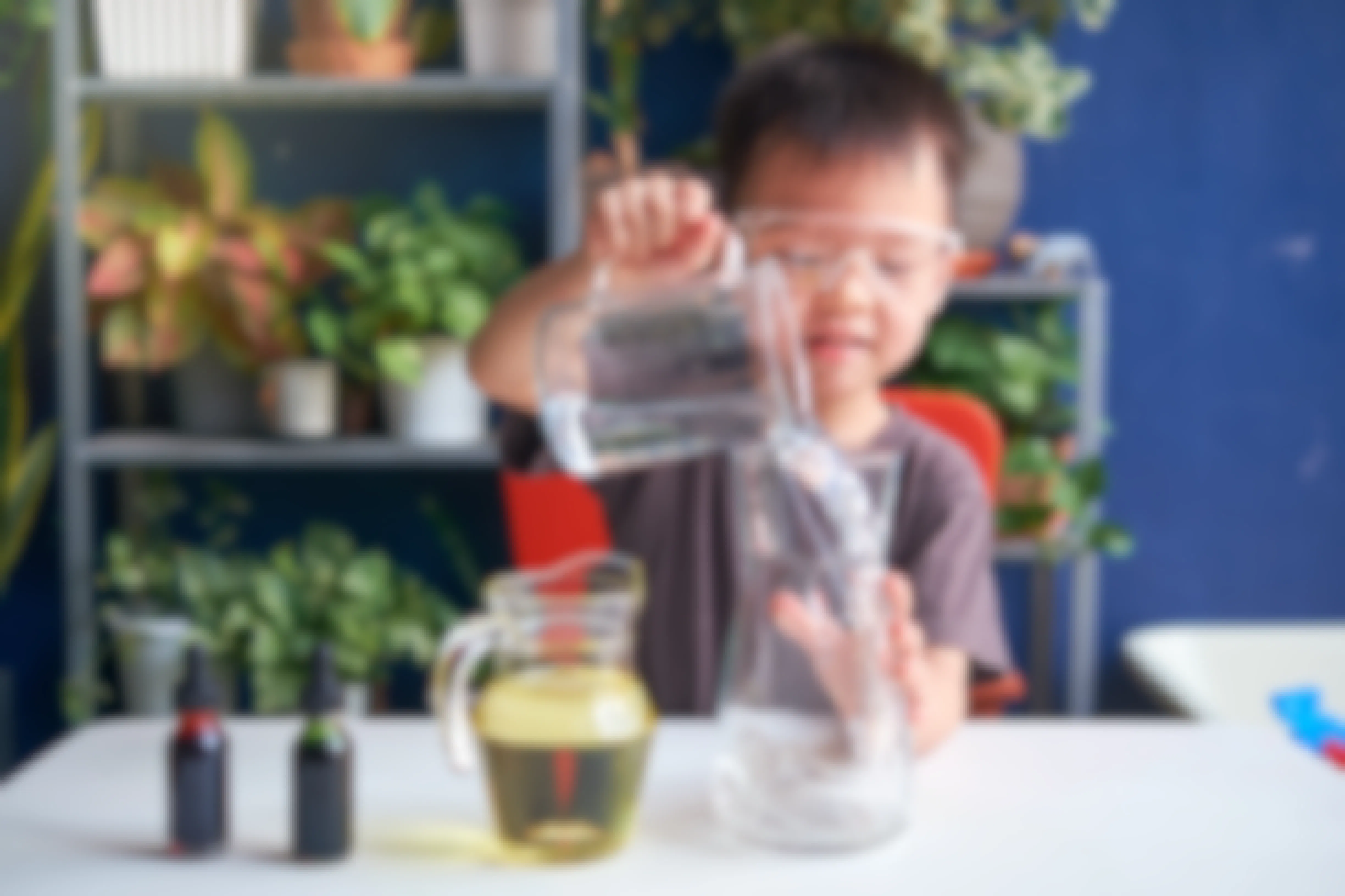 Child with goggles on purs a liquid into a beaker