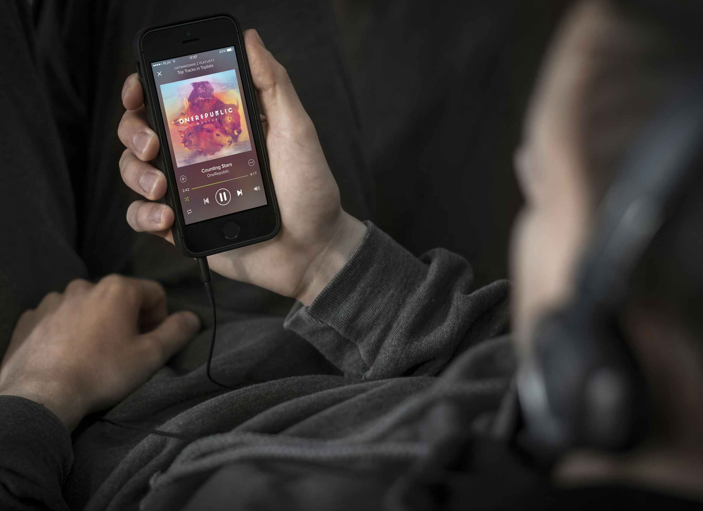 a man laying down with his headphones on and holding his phone while listening to a song on Spotify