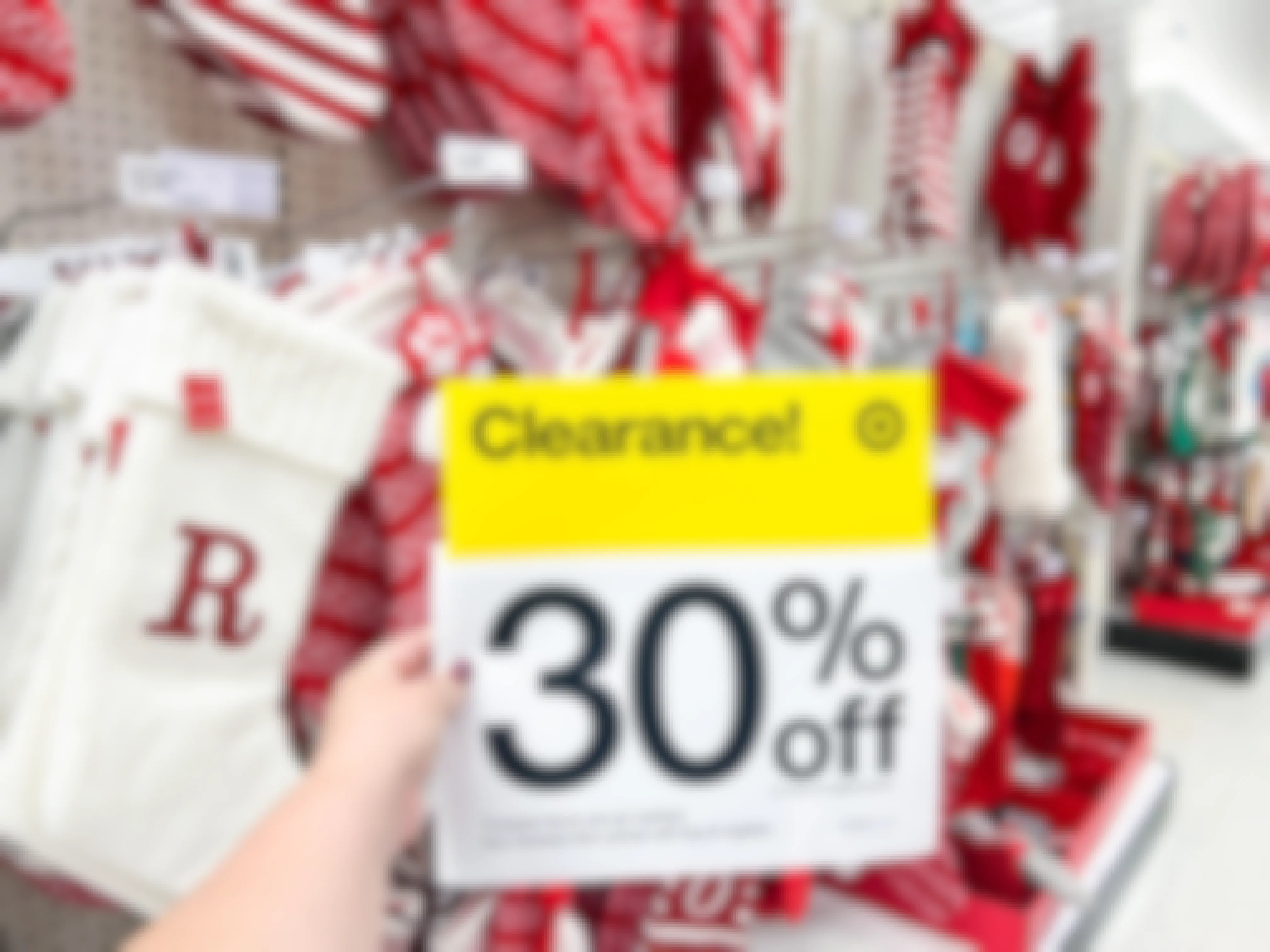 Someone holding a 30% off sign in front of a display of Christmas stockings at Target