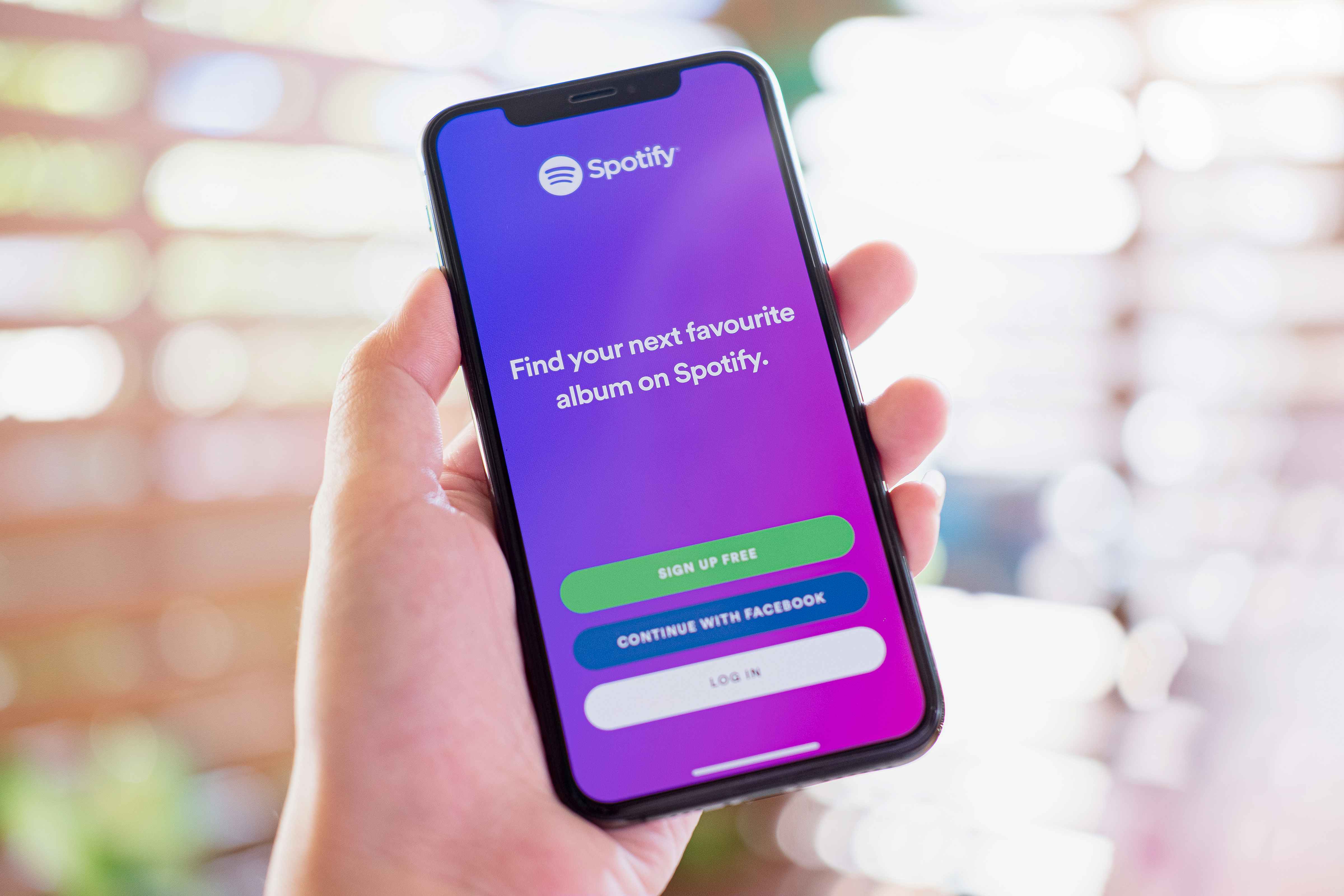 person holding a phone that shows the log in screen for Spotify
