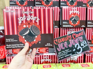 hand holding a box of Trader Joe's Candy Cane Joe-Joe's in front of display with sale price in front