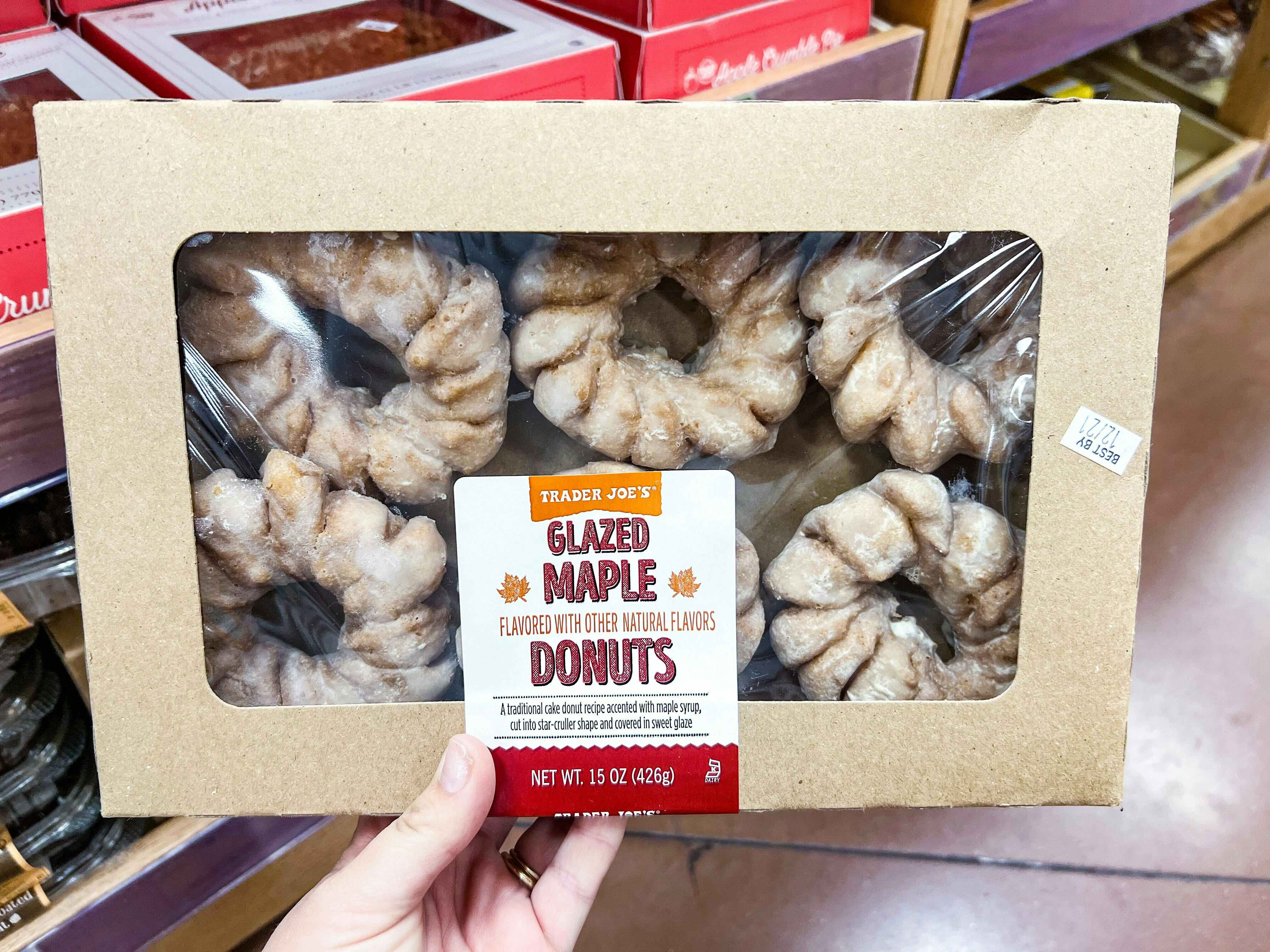 hand holding a box of Trader Joe's Glazed Maple Donuts in store
