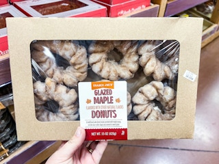 hand holding a box of Trader Joe's Glazed Maple Donuts in store