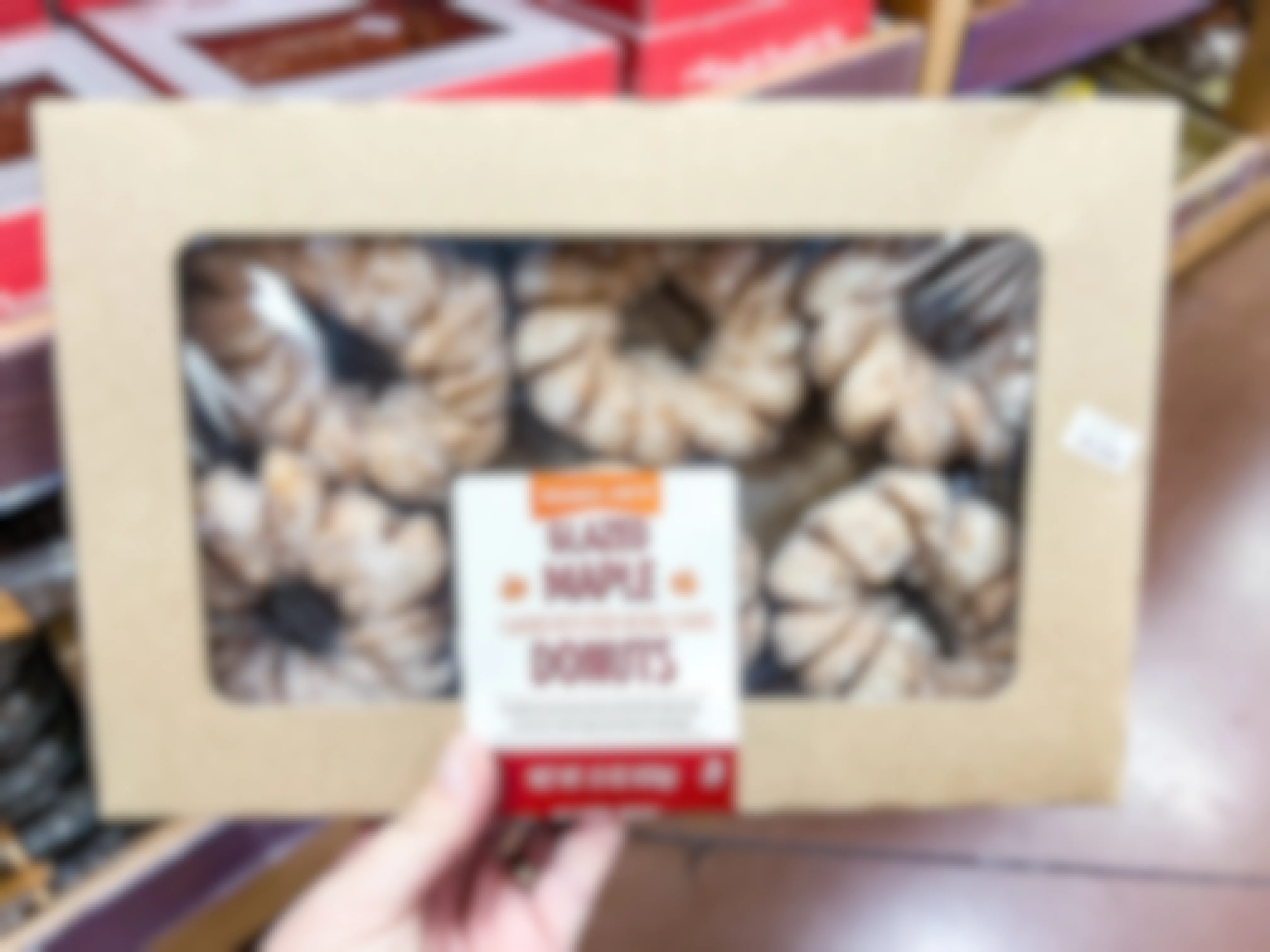 hand holding a box of Trader Joe's Glazed Maple Donuts in store