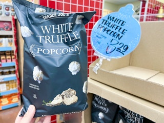 bag of Trader Joe's White Truffle Popcorn held up in front of price sign