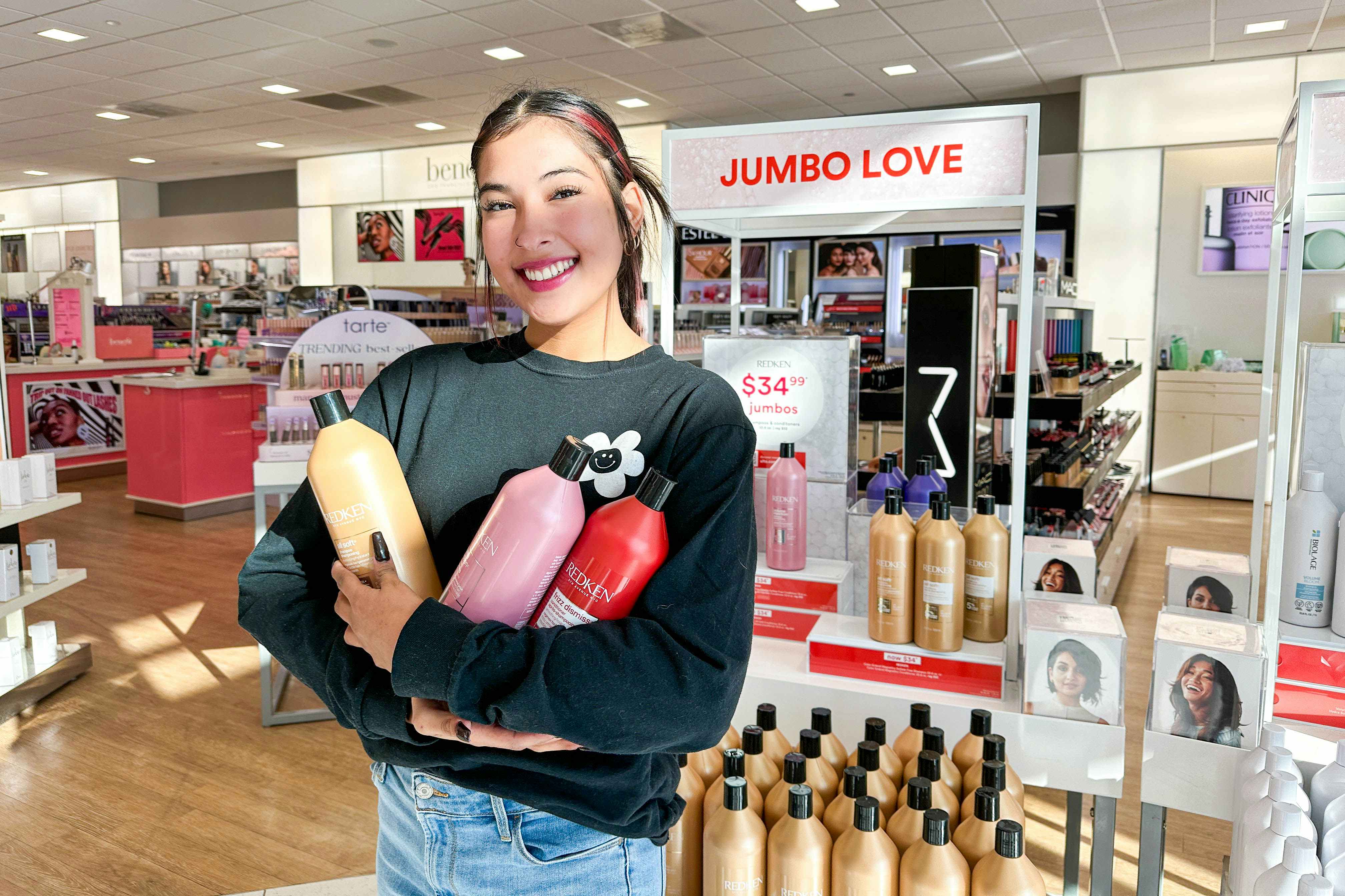 a woman holding jumbo litters of shampoo in ulta