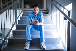 Male Nurse on mobile phone while sitting on stairs