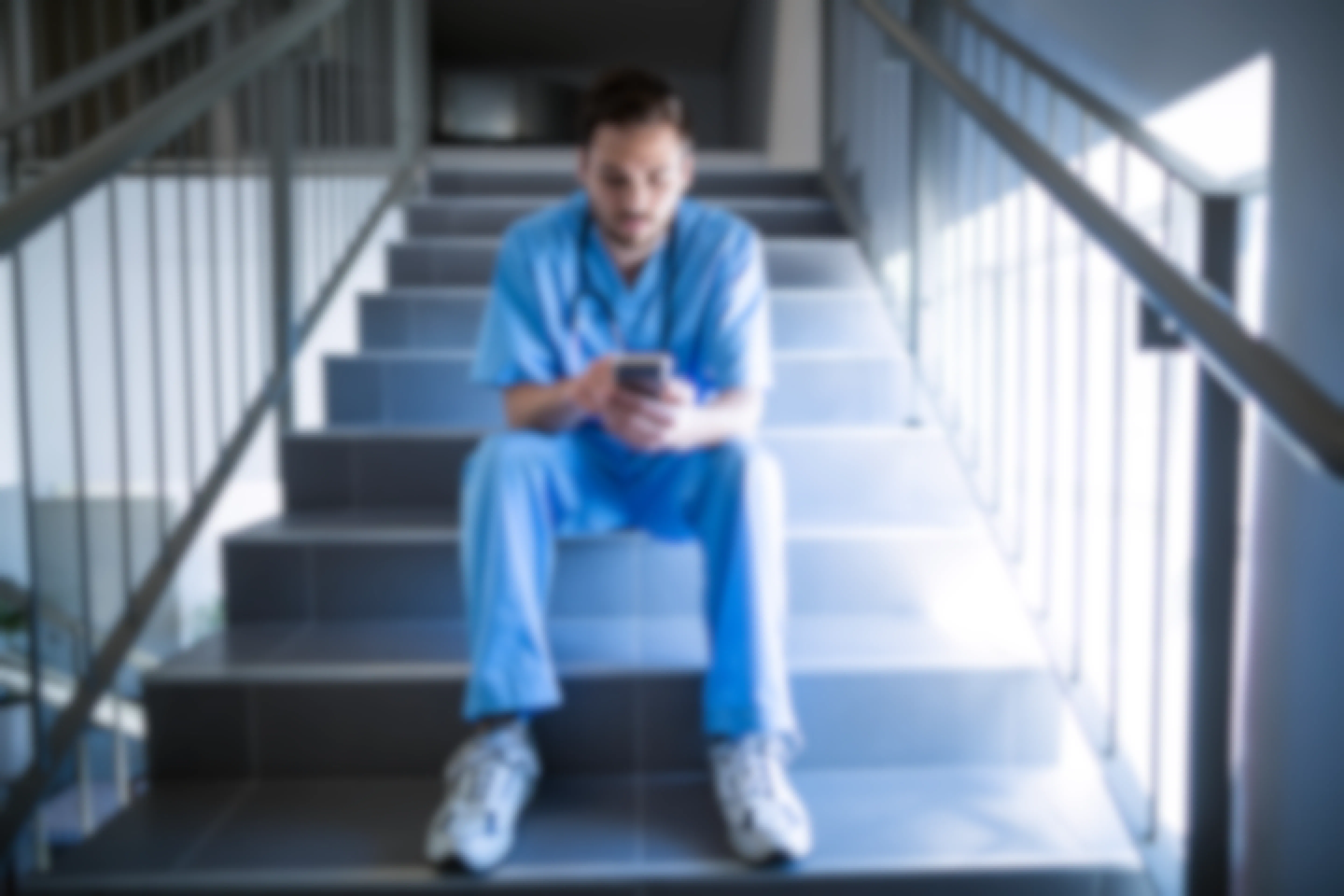 Male Nurse on mobile phone while sitting on stairs
