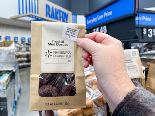 Someone holding up a bag of donuts in the The Walmart bakery showing the label that says Freshness Guaranteed