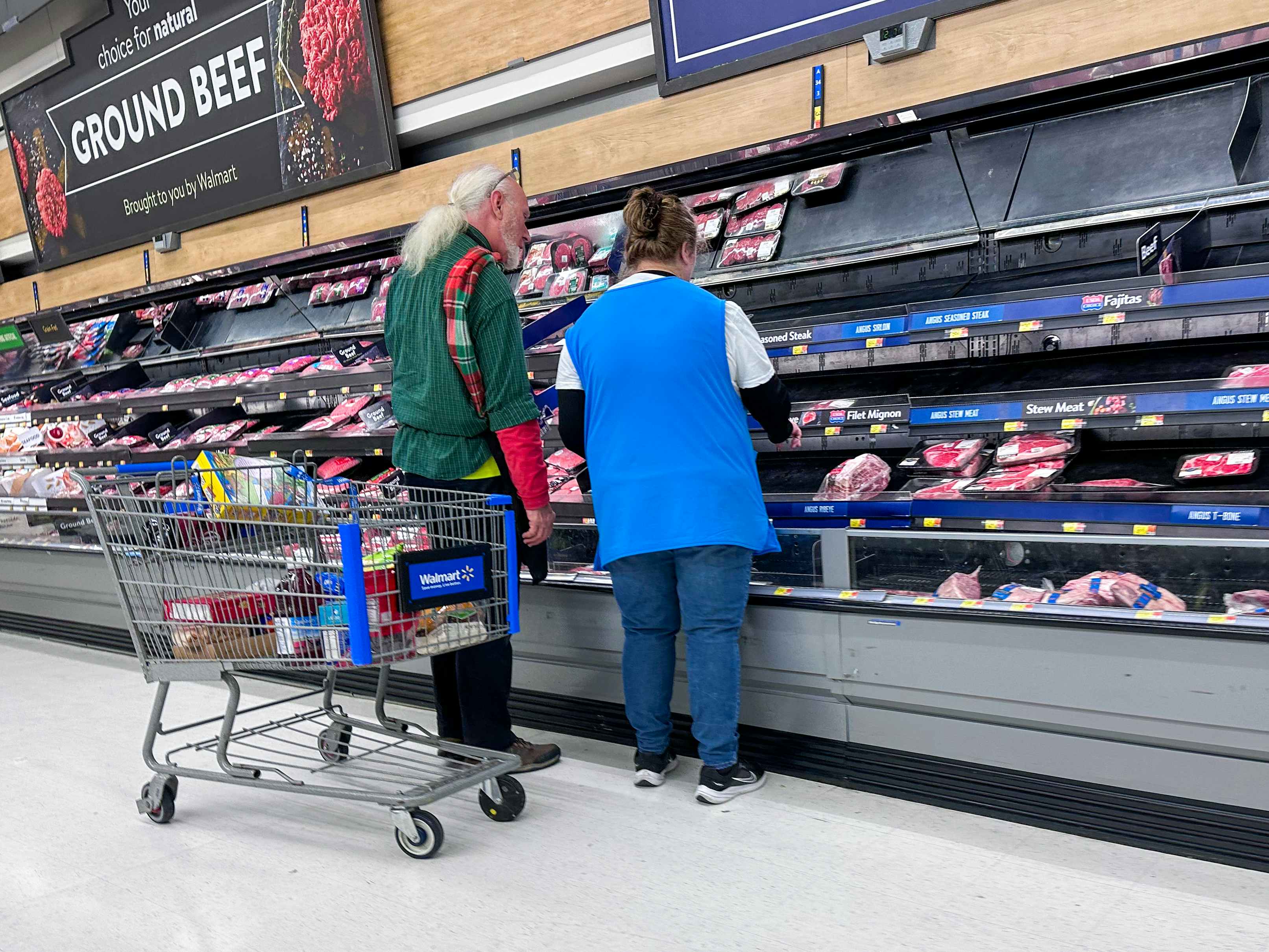 Two Walmart employees stocking the shelves of meat