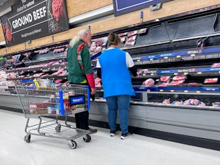 Two Walmart employees stocking the shelves of meat
