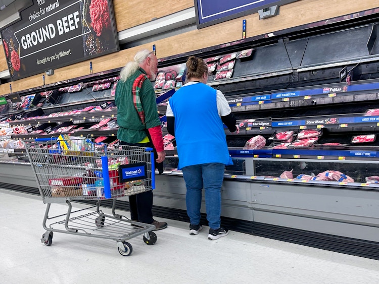 Two Walmart employees stocking the shelves of meat