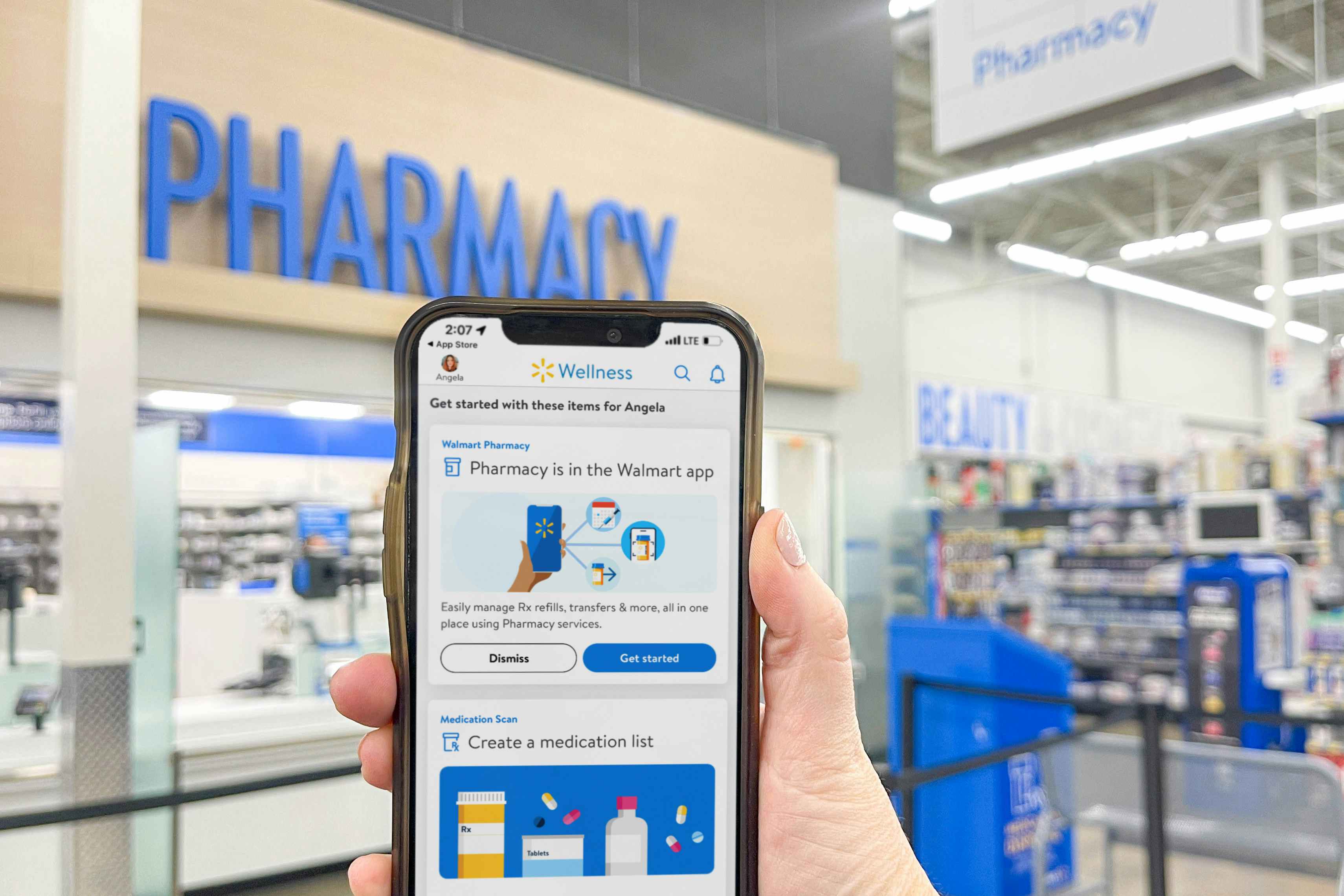 a person holding a phone with the walmart wellness app in front of the walmart pharmacy 
