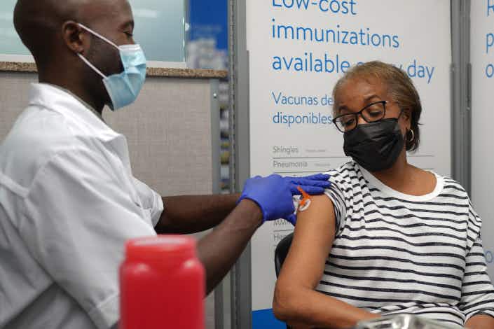 walmart pharmacist giving a woman an immunization shot 