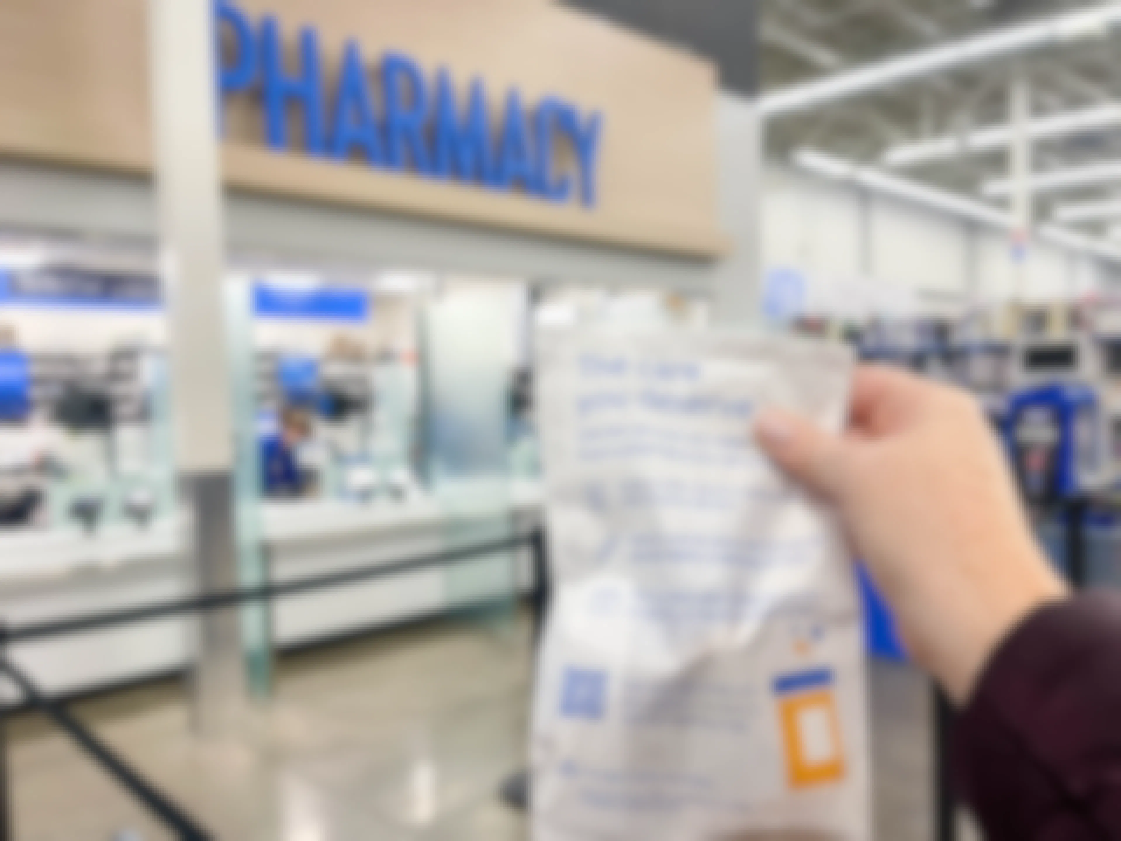 a person holding a refill bag in front of the walmart pharmacy