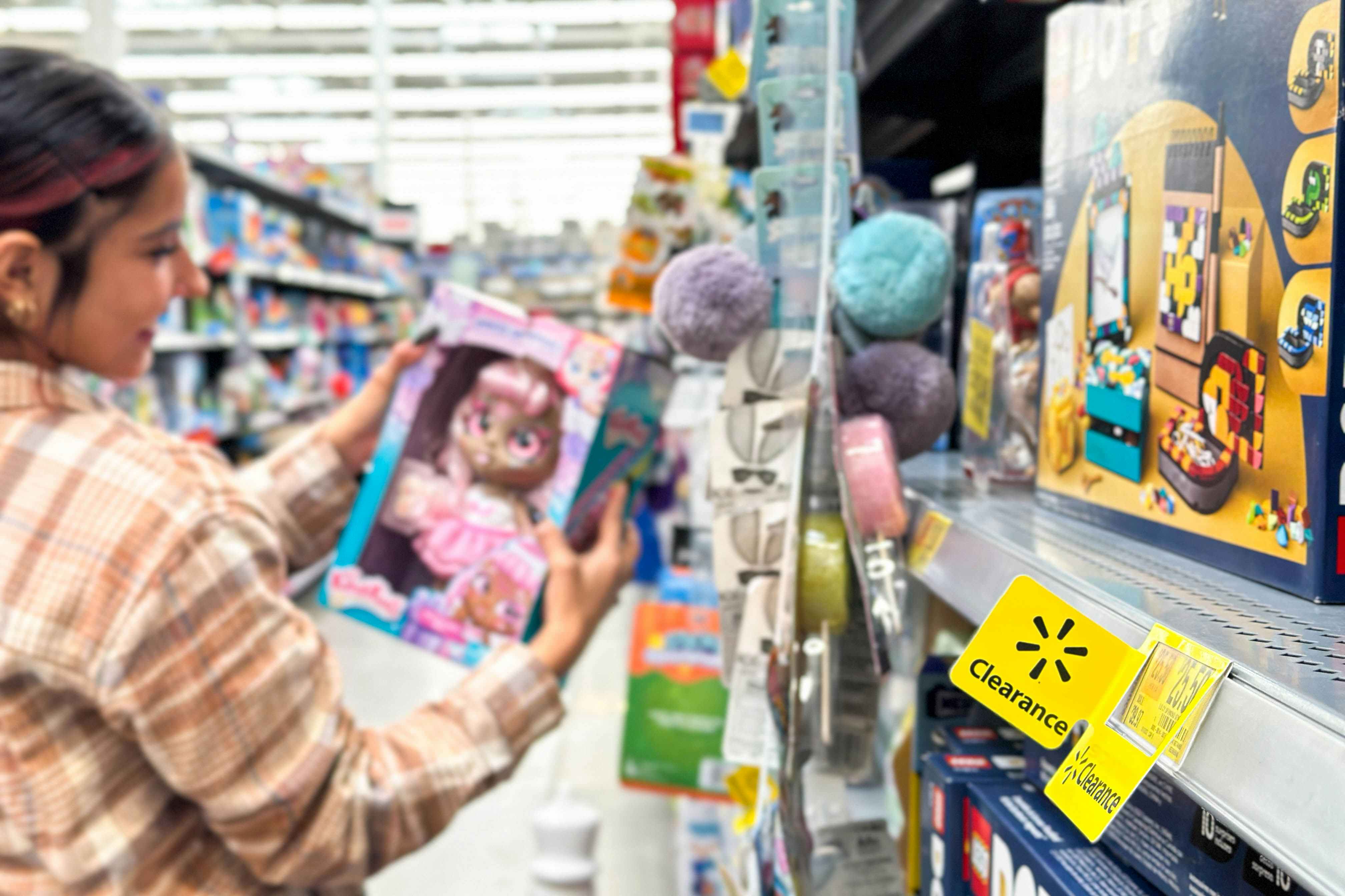 a woman looking at a doll in the walmart toy clearance area