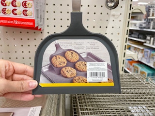 A Wilton Big Cookie Spatula held out by hand while it's hanging from a rack.
