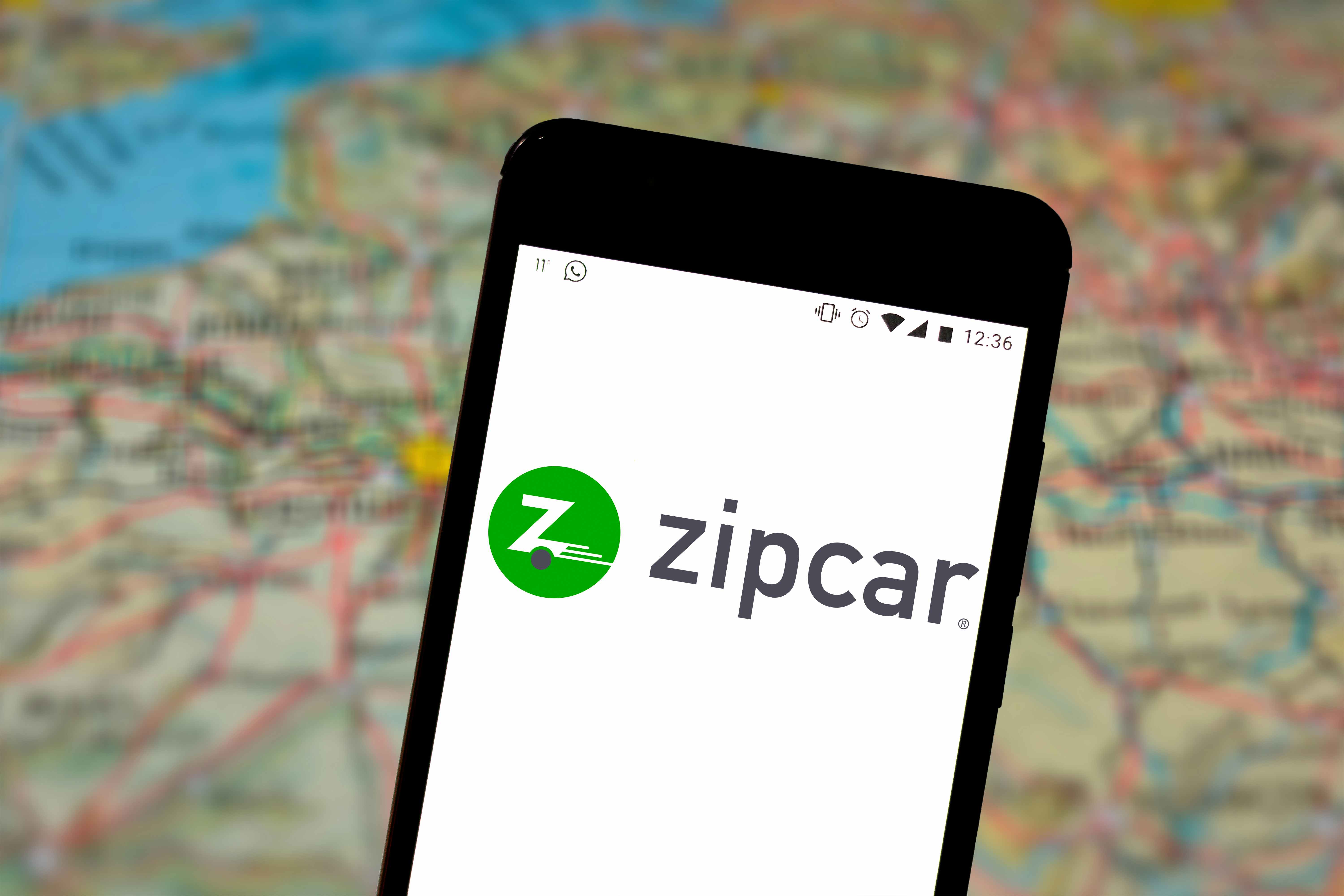 Zipcar logo on iphone with a blurred map as the background