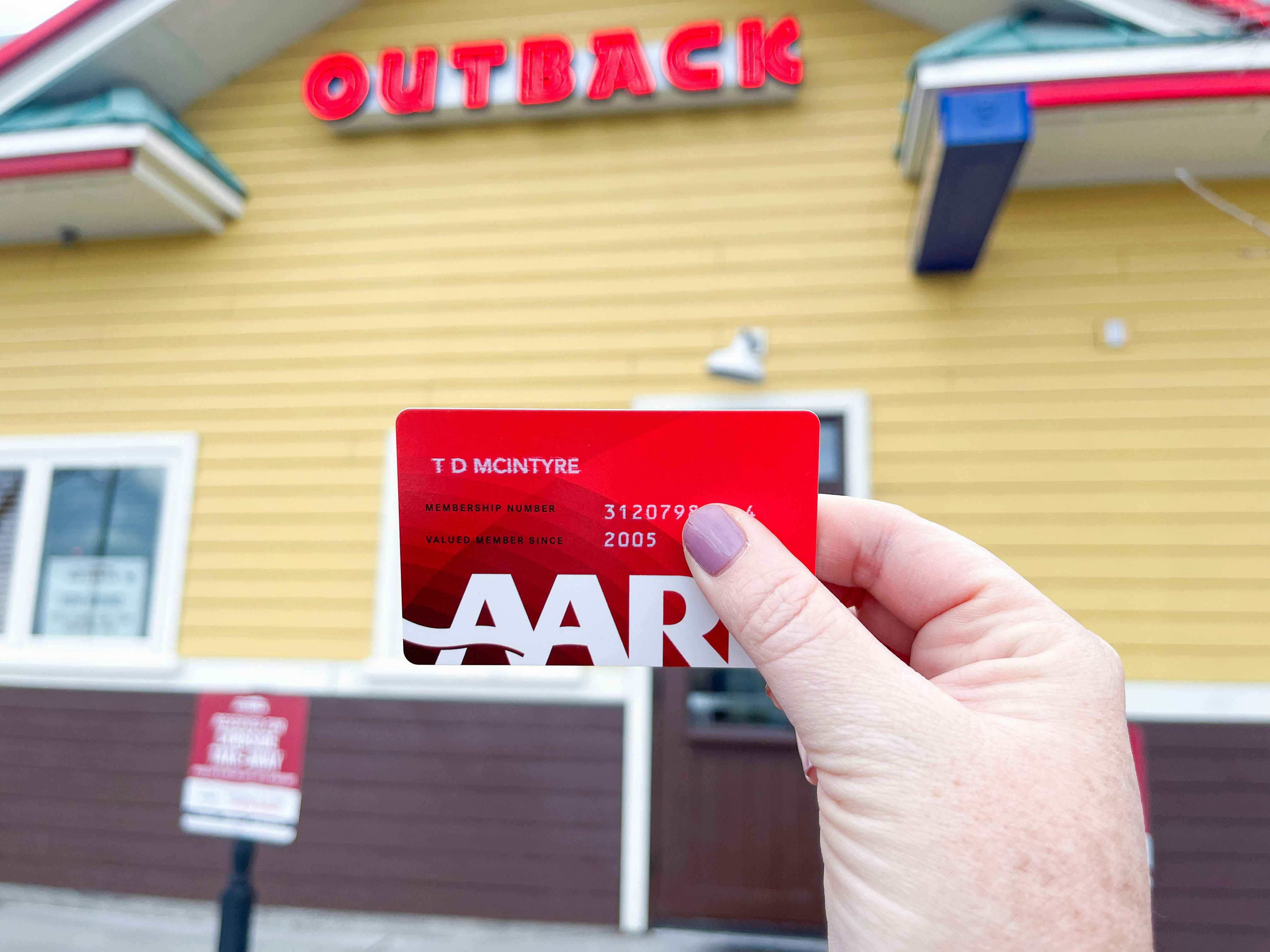 an aarp card being held outside an outback steakhouse
