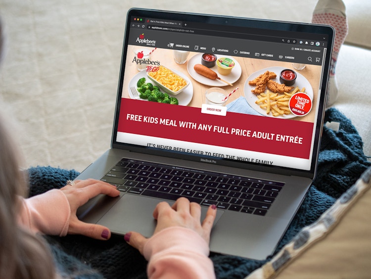 A person looking at the Applebee's site webpage about their Kids Eat Free offer