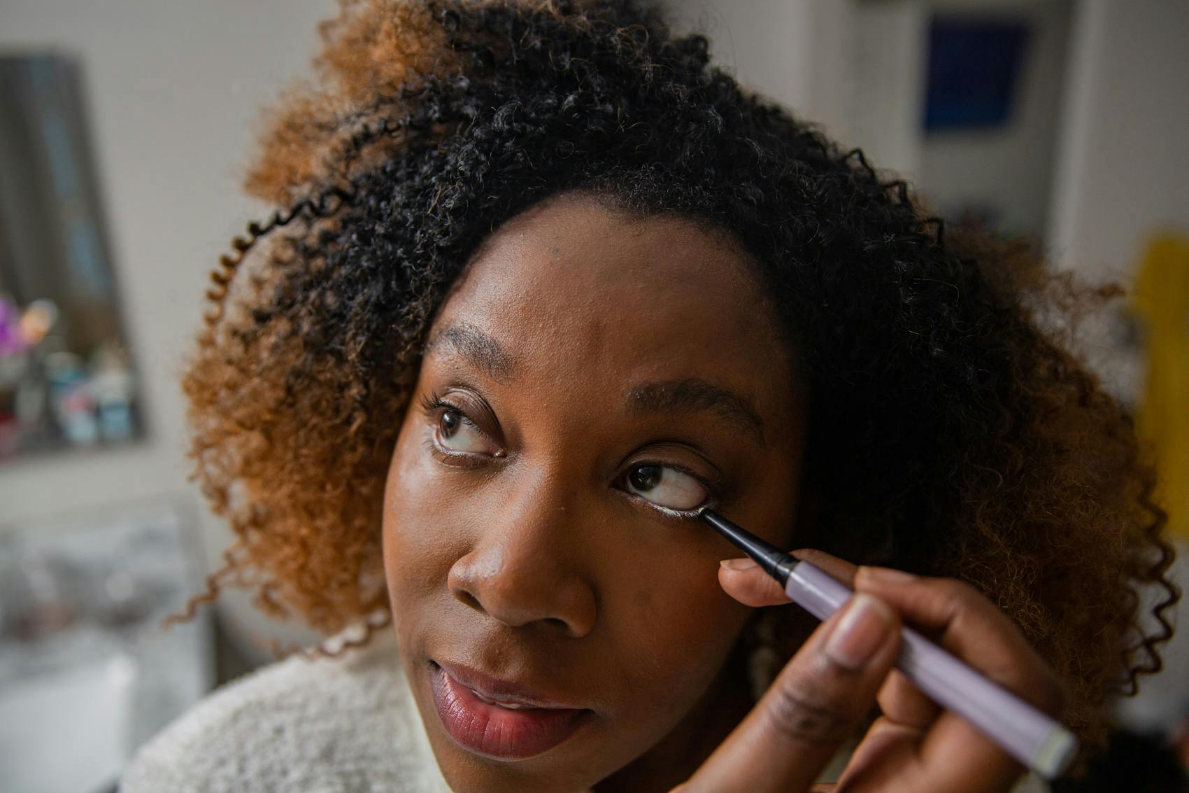 Woman adding white eyeline to her bottom eye lid