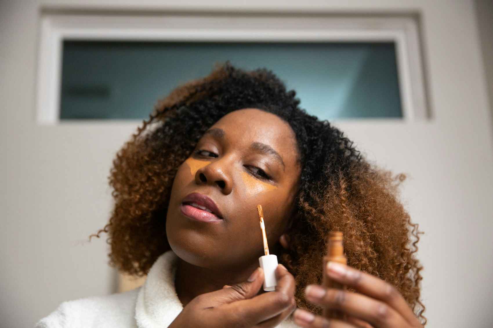 Woman applying concealer to their face