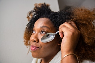 Woman using cold spoon to help with puffiness