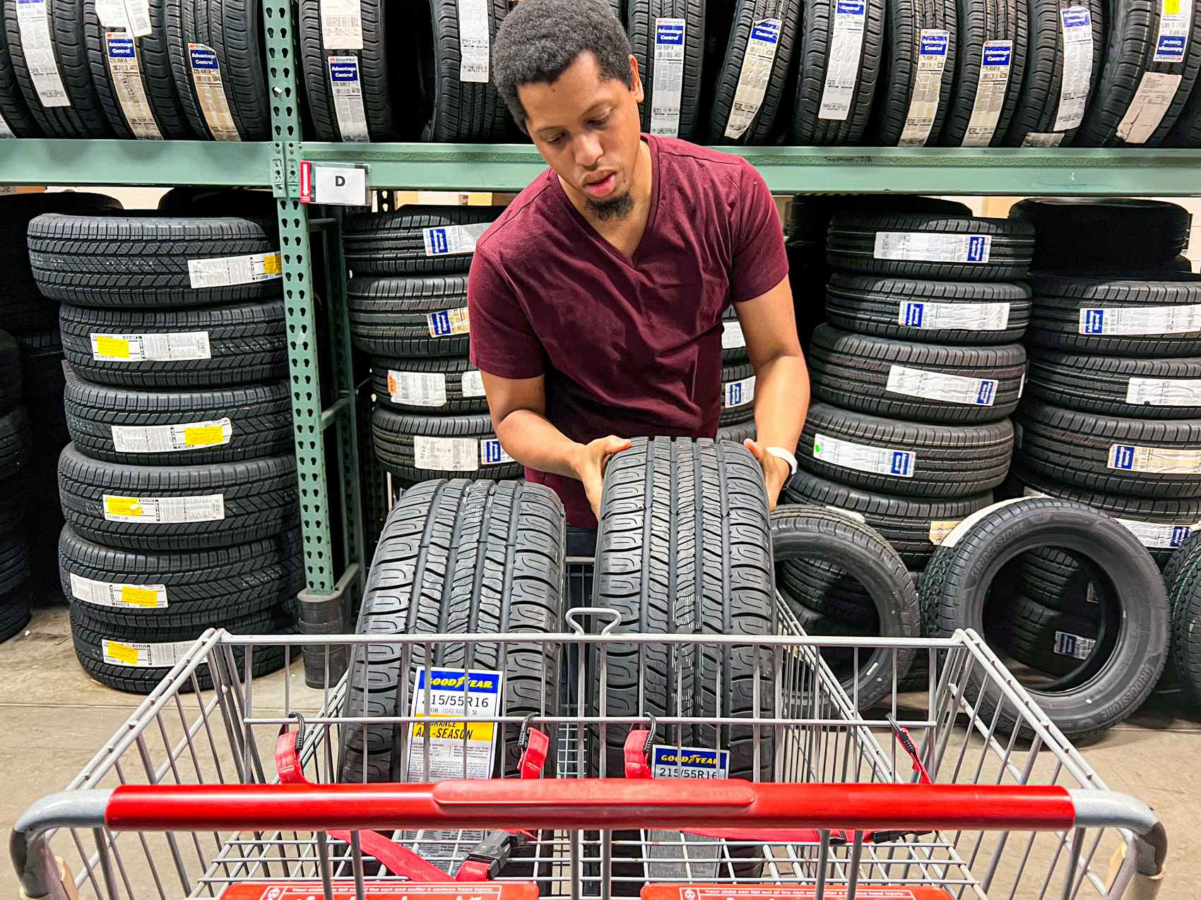 Person placing two tires into a Bj's shopping cart