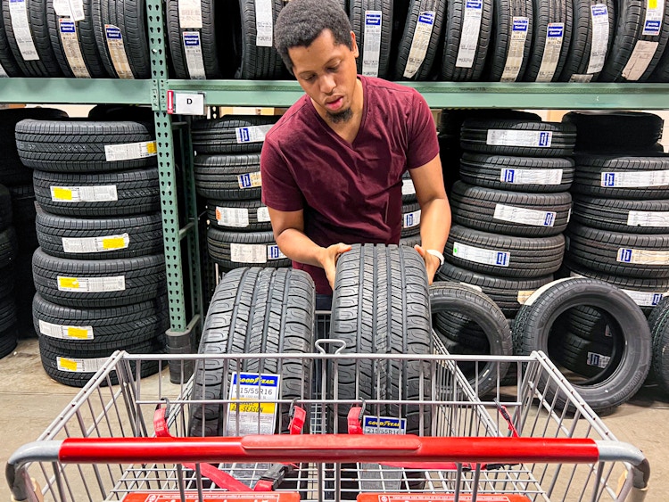 Person placing two tires into a Bj's shopping cart