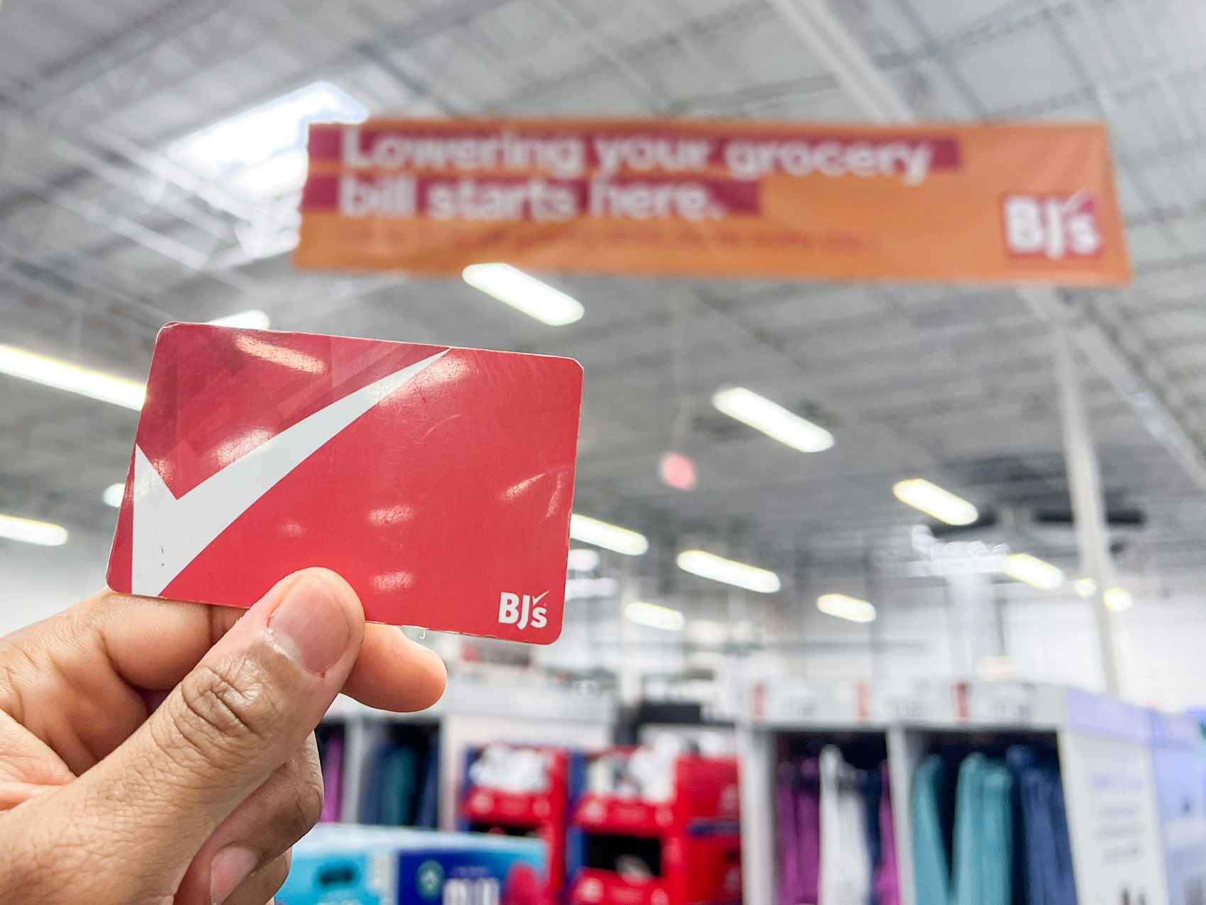 Person holding a Bj's Membership card inside a Bj's Warehouse