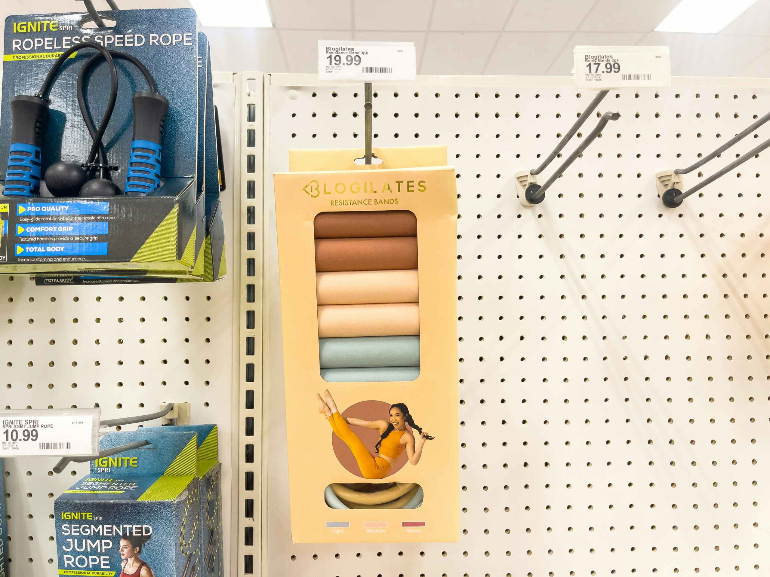 A 3 pack Blogilates resistance bands hanging from a store rack.