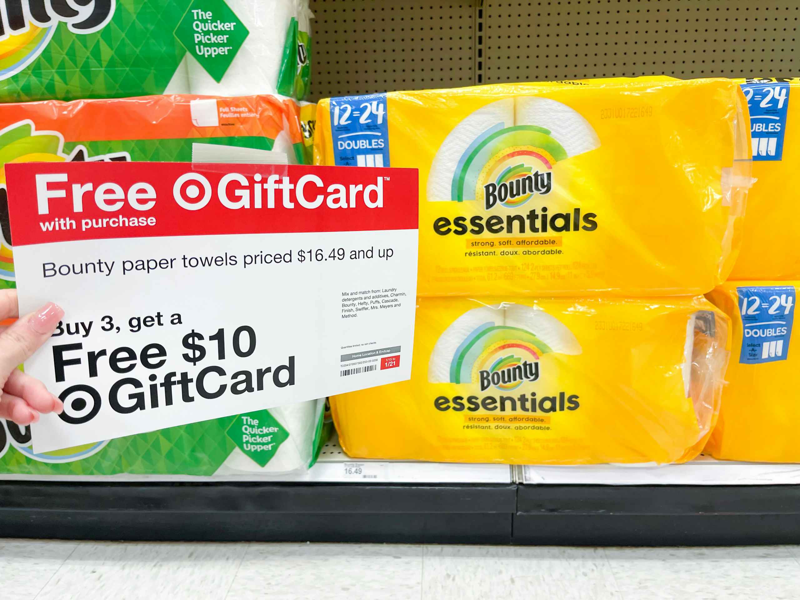 A Free Giftcard sign held out by hand in front of rolls of Bounty Essentials paper towels.