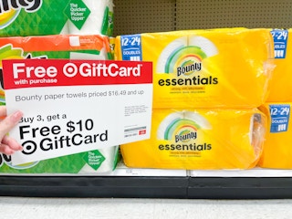 A Free Giftcard sign held out by hand in front of rolls of Bounty Essentials paper towels.
