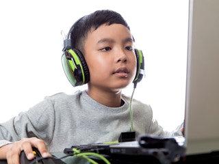 child with headphones working on computer
