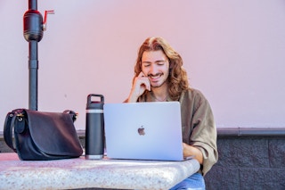 Person with long hair and a nose piercing looking at their laptop